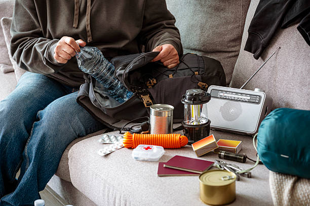 Woman filling emergency backpack with disaster emergency supplies. Preparing for crisis or disaster Woman filling emergency backpack with disaster emergency supplies. Preparing for crisis or disaster. High resolution 42Mp studio digital capture taken with SONY A7rII and Zeiss Batis 40mm F2.0 CF lens earth first aid stock pictures, royalty-free photos & images