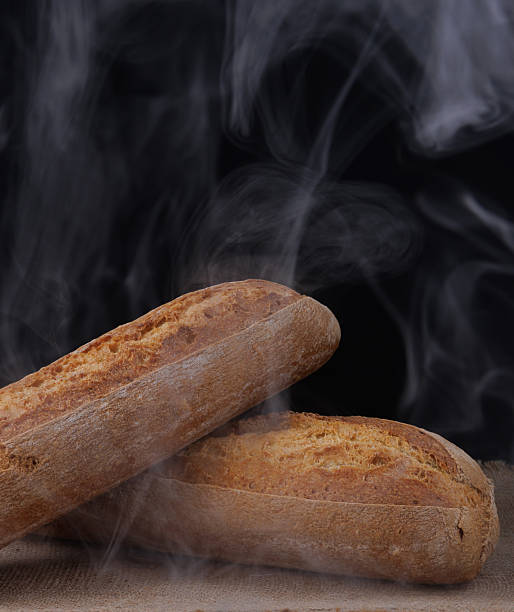 istock Baguette steaming on dark background. Fresh hot bread. 2209169421