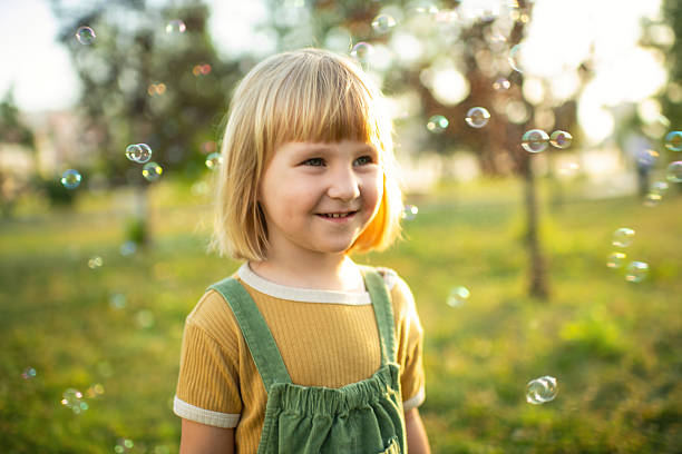 istock Little girl playing in a park with soap bubbles 2209177379