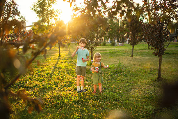 Children playing in a park and blowing bubbles in summer