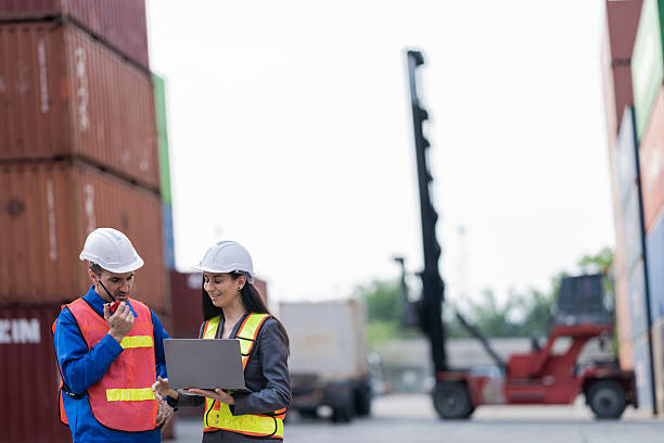 istock Two logistics workers man and woman discuss operations at a busy shipping container yard. successful coordination in freight, transportation, and supply chain operations 2209178738