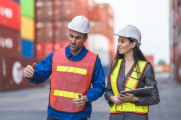 istock Two logistics workers man and woman discuss operations at a busy shipping container yard. 2209179667