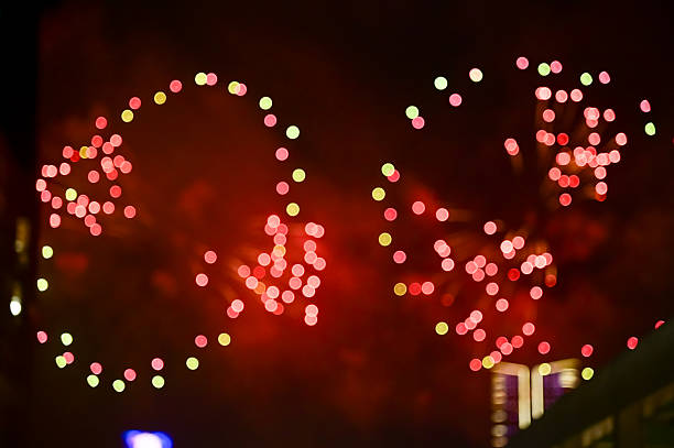 Bokeh effect of colorful fireworks display in the night sky. Real fireworks background.  Abstract of real shining fireworks against black background. Glowing fireworks show for celebration.