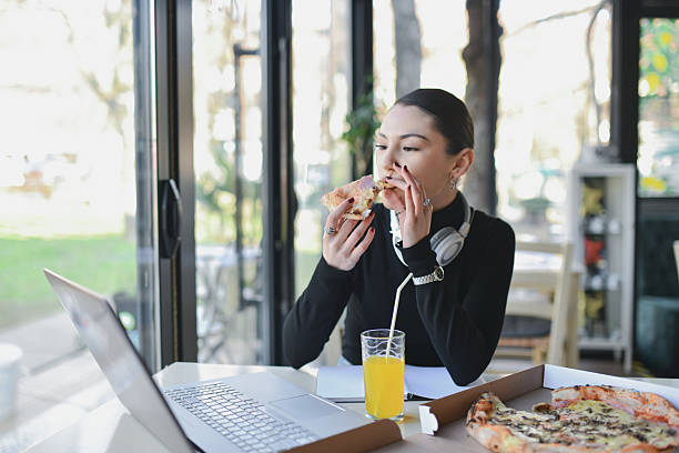 istock Beautiful Woman Indulging in Pizza While Watching Videos on Laptop 2209181009