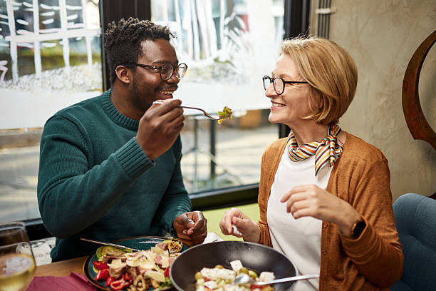 istock Young diverse man feeding senior woman on romantic dinner date at restaurant. 2209181864