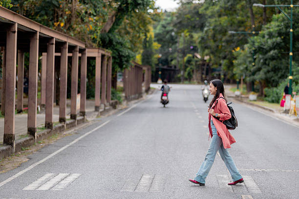 istock Confident young student walking on a crosswalk in Thailand, enjoying her independence and urban lifestyle 2209182385