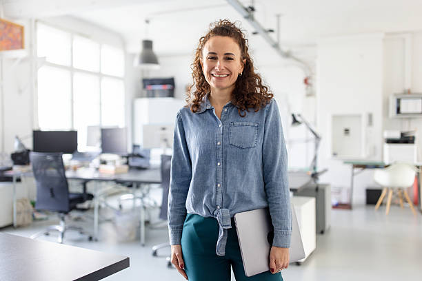 istock Woman professional standing with laptop and smiling at work 2209182518