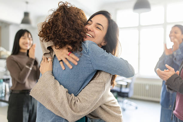 istock Happy female colleagues embracing at office celebration with team clapping 2209182567