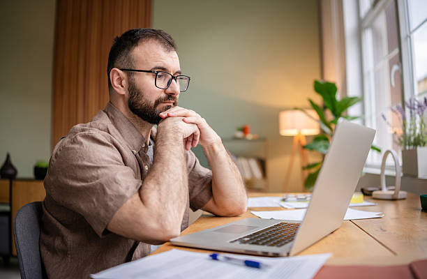 istock Young man engaged in freelance work at home while using a laptop in a cozy apartment setting 2209186438