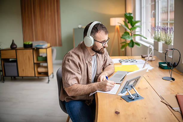 istock Young man working from home at a desk while focused on writing and using technology in a cozy apartment setting 2209187926