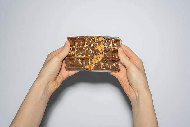 istock Famous Dubai chocolate with peanut butter, caramel and kadaif broken in woman's hands. Confectionery handmade sweets, chocolatier 2209188002