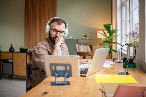 istock Young man working from home at a well-organized desk with laptop and tablet while engaging in freelance projects 2209188161