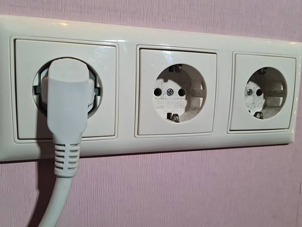istock Close-up shot of electrical outlets on a pink wall with a plug inserted 2209190379