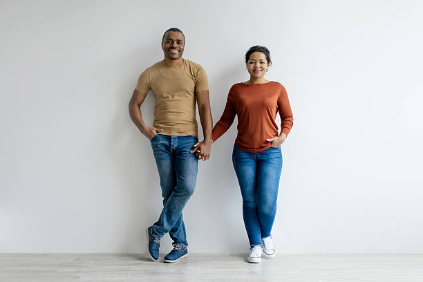 istock Smiling young black couple holding hands and smiling at camera 2209190980