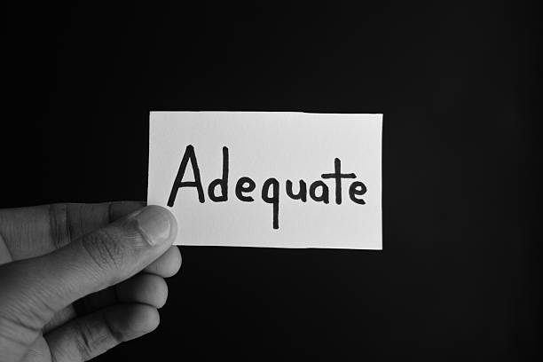 istock Hand holding a paper card with the word ADEQUATE 2209191954