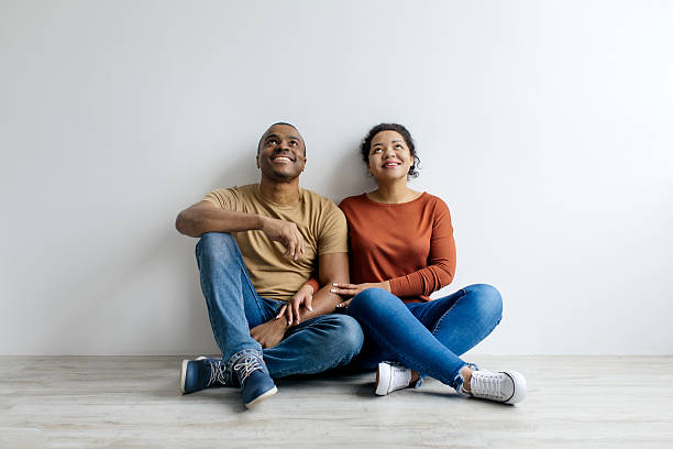 istock Couple sitting together on the floor, casually looking up at copy space 2209192013