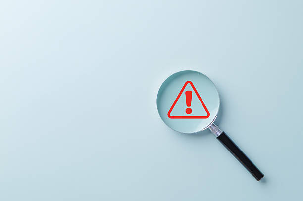 Warning Alert Symbol. A red warning symbol under magnifying glass, symbolizing risk detection, safety alerts, issue investigation, or system monitoring in business and technology contexts.