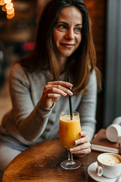 istock Young woman drinking orange juice in a cafe 2209194549