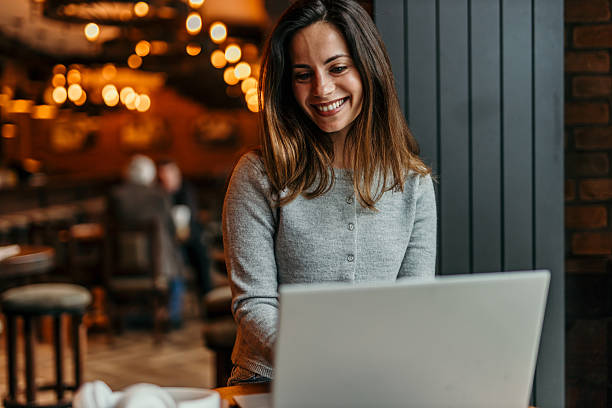 istock Young Woman Working on Laptop in Cozy Cafe 2209195556