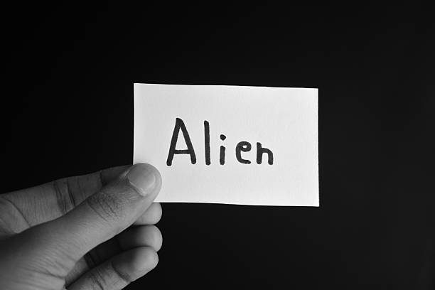 istock Hand holding a paper card with the word ALIEN 2209195600