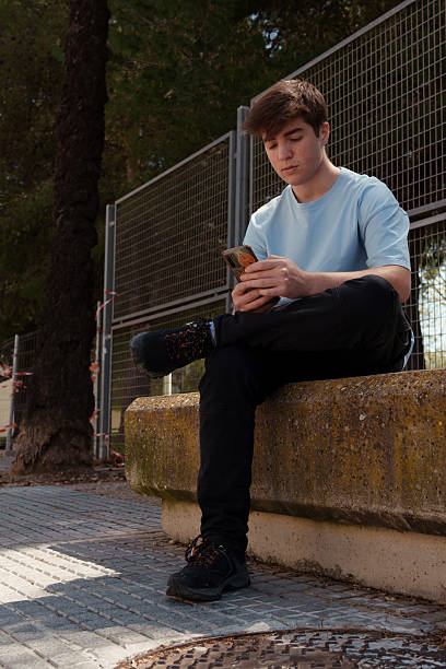 istock Young with your mobile while sitting on a concrete bank 2209195604