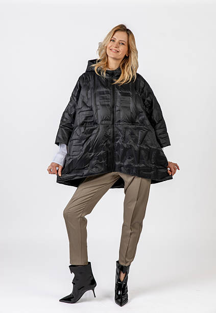 istock Smiling Caucasian Woman Modeling Black Coat and Stylish Attire in Studio Setting 2209195638
