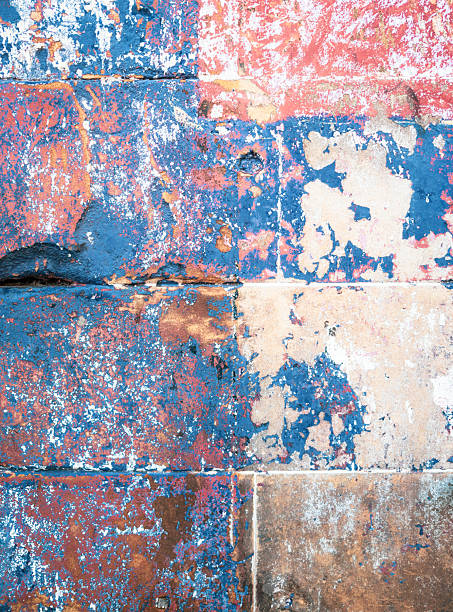 Macro image of a section of worn and aged blue and red paint over an old stone wall.
