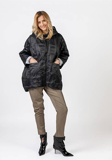 istock Smiling Caucasian Woman Modeling Black Coat and Stylish Attire in Studio Setting 2209196452