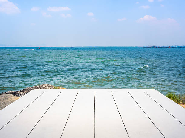 istock Summer vacation concept with seascape background for placed products. Empty white wood plank top table on tropical sea ocean scene on open blue sky and white clouds, horizontal abstract background. 2209196640