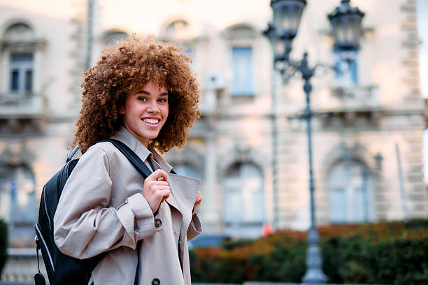 istock Smiling student walking in the city carrying backpack 2209196642