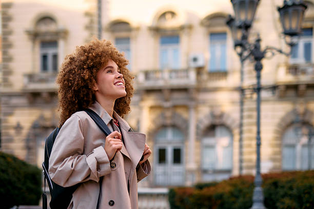 Smiling student looking up at university building in a campus