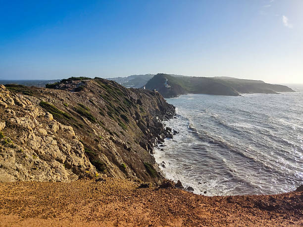 istock Dramatic coastline view with rugged cliffs, ocean waves, and a clear blue sky. Evokes a sense of adventure, natural beauty, and exploration. Ideal for travel and nature themes. 2209196731