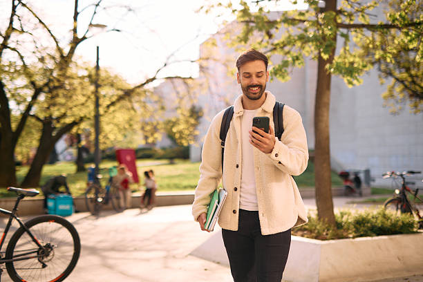 istock University student walking and using smartphone in campus park 2209196788