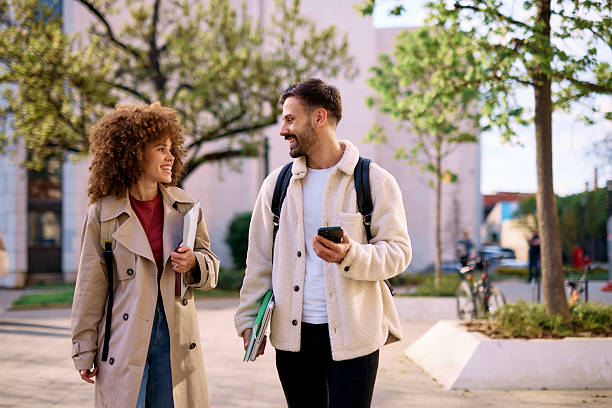 istock Two cheerful students walking and talking on university campus 2209196803