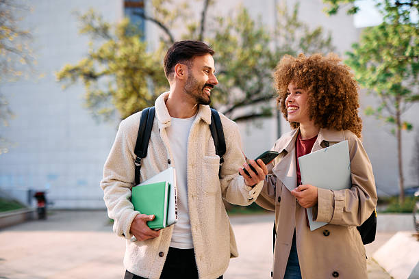 istock Two cheerful students walking and talking outside of university building 2209196830