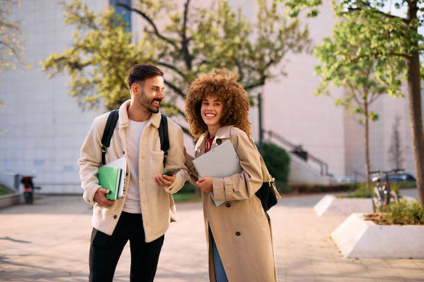 istock Two cheerful students walking and talking together outside of university building 2209196833