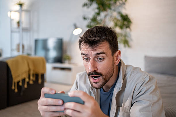 istock Excited man playing mobile game at home living room 2209199283