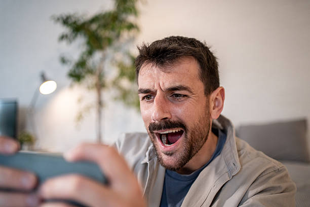 istock Excited man playing mobile game at home 2209199401
