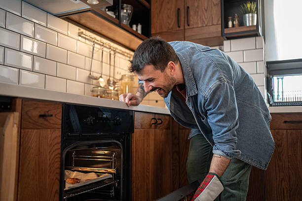 istock Happy man checking food baking in oven at home 2209200256