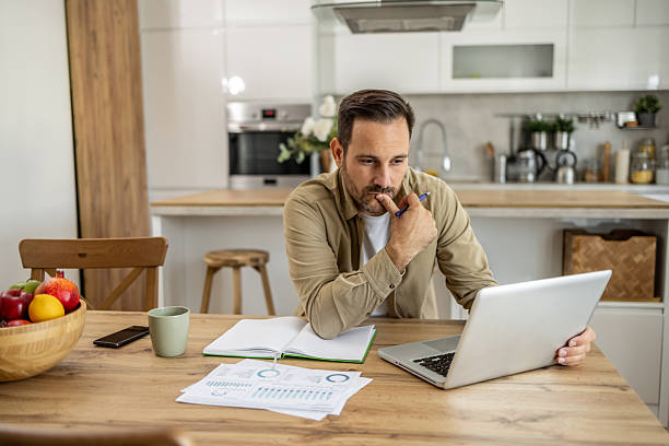 istock Focused businessman working from home analyzing charts and data on his laptop 2209200377