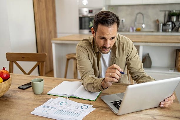 istock Focused businessman working from home analyzing charts and graphs on his laptop 2209200387