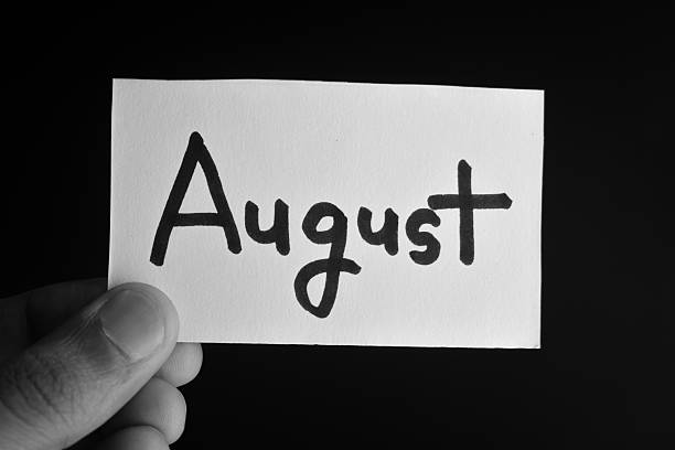 istock Hand holding a paper card with the word AUGUST 2209203616