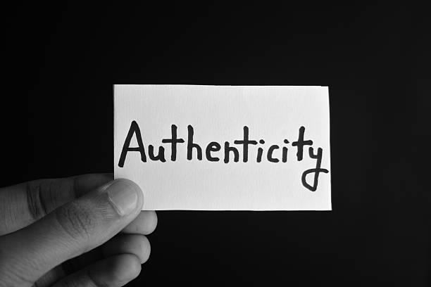 Hand holding a paper card with the word AUTHENTICITY