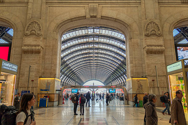 The image shows a platform at Milano Centrale railway station with several people getting their next connection.