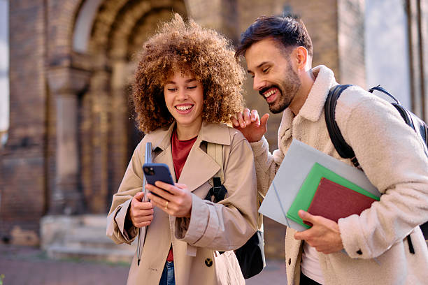 istock Two cheerful students looking at smartphone in front of university building 2209213196