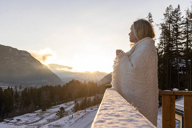 istock Mature woman enjoys sunrise on cabin deck 2209214009