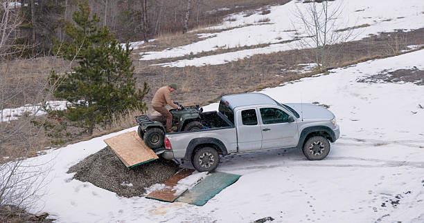 Aerial view of man unloading ATV from truck in winter, Crowsnest Pass, Alberta
