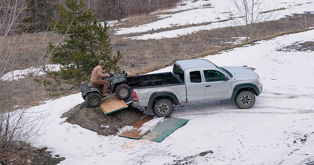 Aerial view of man unloading ATV from truck in winter, Crowsnest Pass, Alberta