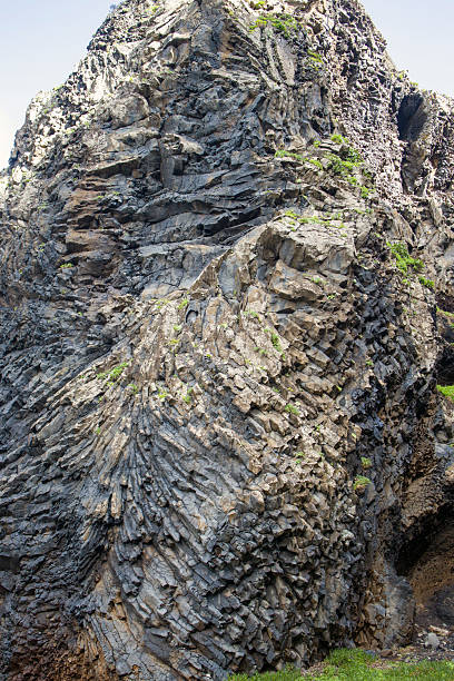 istock Unique rock formation showcasing natural textures and patterns in a coastal area with vibrant greenery under a clear sky 2209222870