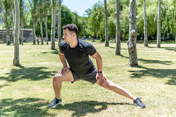 istock Young man stretching his legs in a park before starting to exercise 2209225822